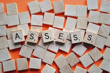 scrabble tiles that read "ASSESS" on top of many blank tiles