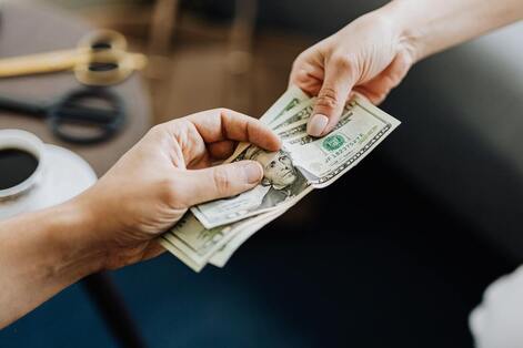 image of two people's hands exchanging cash money