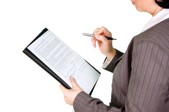 woman looking over subgrant agreement with pen in her hand
